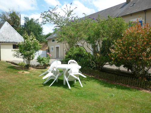 two white chairs and a table in a yard at La Parisiere in Gavray