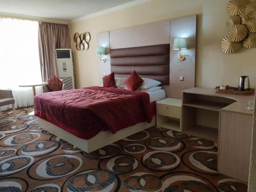 a hotel room with a bed with a red bedspread at Nicon Luxury Abuja in Abuja