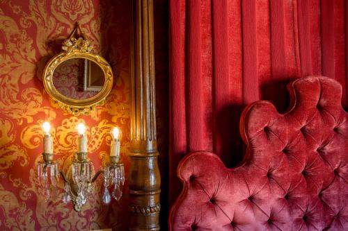 a room with a red wall with a chair and a mirror at Boutique Hotel Campo de' Fiori in Rome