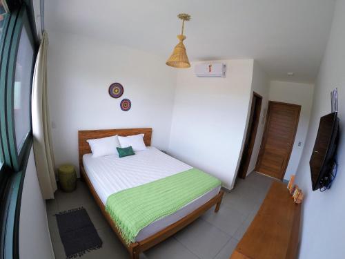 a small bedroom with a bed with a green blanket at Nai'a Suites in Ubatuba