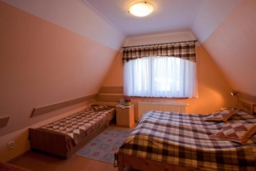 a attic bedroom with two beds and a window at Apartamenty-Wynajem pokoi Zbigniew Tylka in Kościelisko