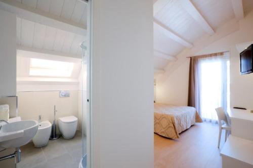a white bathroom with a bed and a sink and a toilet at Hotel Lux in Caorle