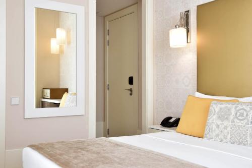 a bedroom with a white bed and a mirror at My Story Hotel Ouro in Lisbon