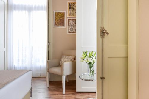 a bedroom with a chair and a table with a vase of flowers at My Story Hotel Ouro in Lisbon