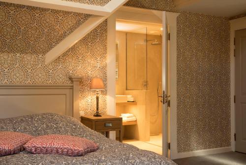 a bedroom with a bed and a bathroom with a shower at Relais & Chateaux Hotel Landgoed Het Roode Koper in Ermelo