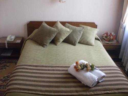 a bed with two towels and two flowers on it at Hotel Mercurio in Punta Arenas