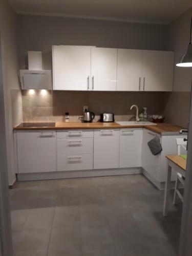 a kitchen with white cabinets and a sink at Apartament Pogodny in Jelenia Góra