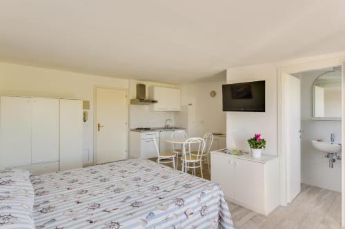 a bedroom with a bed and a kitchen with a sink at Oltremare Appartamenti in Principina a Mare