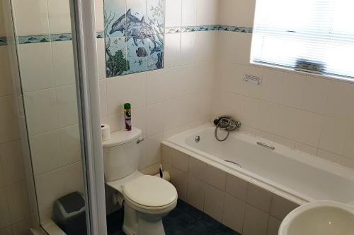 a bathroom with a toilet and a tub and a sink at Fairway 2 Holiday Home in Langebaan