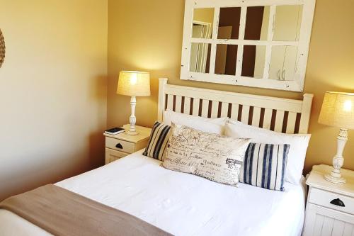 a bedroom with a bed with two lamps and a mirror at Fairway 2 Holiday Home in Langebaan