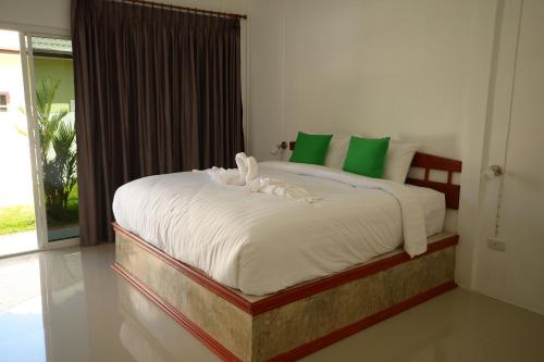 a bedroom with a large bed with green and white pillows at Mrchu Meditation House in Khao Lak