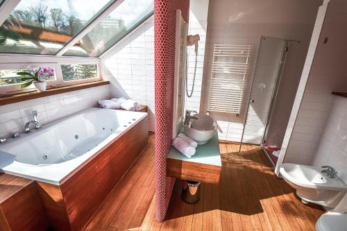a bathroom with a large bath tub and a toilet at Bonvital Hotel Hévíz Superior Adults Only in Hévíz