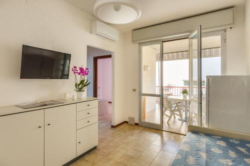 a kitchen with white cabinets and a television and a balcony at Oltremare Appartamenti in Principina a Mare