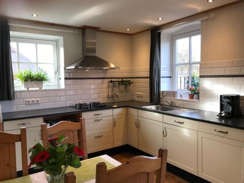 a kitchen with white cabinets and black counter tops at Vijverhoef in Ulicoten