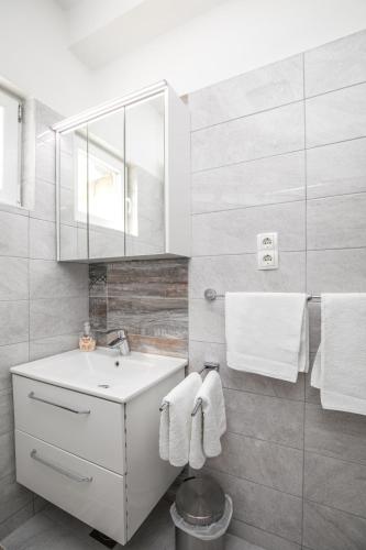 a bathroom with a sink and a mirror and towels at Apartments Renjak in Sukošan