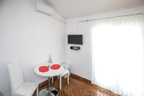 a small white room with a table and a tv at Apartments Renjak in Sukošan