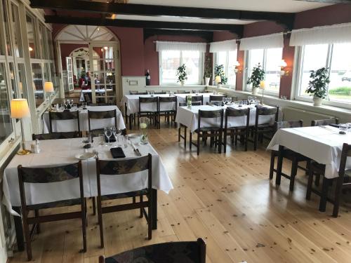 a dining room with white tables and chairs at Hvalpsund Færgekro in Hvalpsund