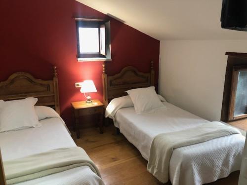 two beds in a room with red walls at Casa Navarro in O Cebrero