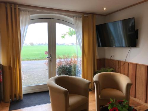 a living room with two chairs and a sliding glass door at Vijverhoef in Ulicoten