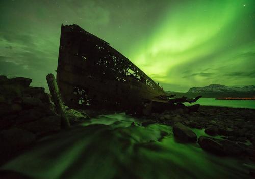 an old building on a beach under a green sky at Hótel Djúpavík in Djupavik