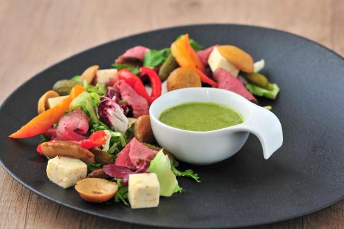 a plate with a salad with a bowl of green dipping sauce at Park Hotel Diament Wroclaw in Wrocław