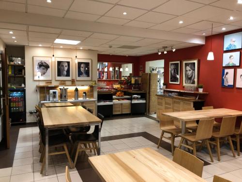 a large kitchen with wooden tables and chairs and red walls at Villa Val Senart 1ere Avenue in Quincy-sous-Sénart