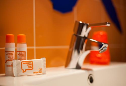 a bathroom sink with two bottles of toothpaste and a faucet at Hotel Made Inn in Portimão