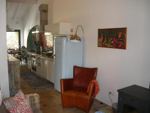 a living room with a chair and a kitchen at Casa do Gato in Ferragudo