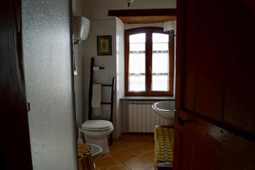 a bathroom with a toilet and a sink and a window at La Petriola Casa Vacanze in Gubbio