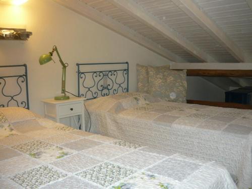 a bedroom with two beds and a lamp on a night stand at Casa do Gato in Ferragudo