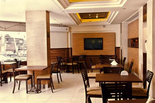 a restaurant with tables and chairs and a flat screen tv at Marble Tower in Beirut