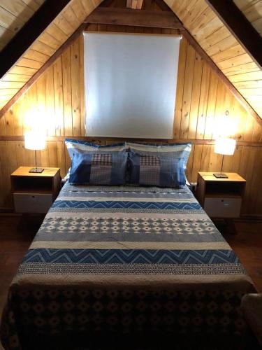 a bedroom with a large bed with two lamps at Cabañas Rosmar in Colón