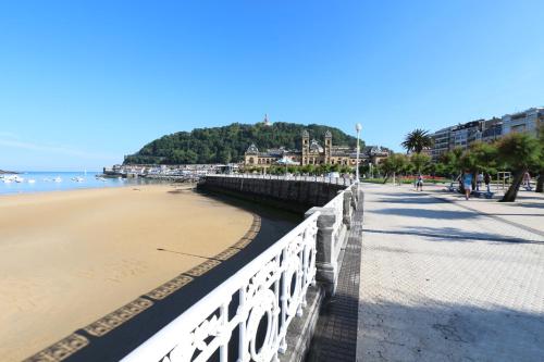 a beach with a white fence next to the ocean at Modern & spacious apartment near La Concha Bay in Donostia-San Sebastián