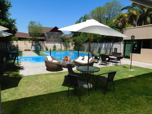 een tafel en stoelen met een parasol naast een zwembad bij Hotel Mar Andino in Rancagua