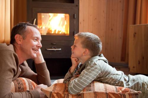 a man and a boy sitting in front of a fireplace at Ferienpark Müritz in Rechlin