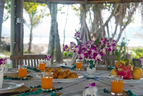 a table with plates of fruit and flowers on it at Kalim Beach House - Private Beach & Pool in Patong Beach