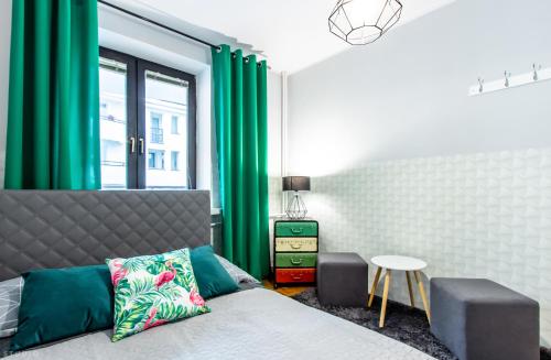 ワルシャワにあるClickTheFlat Wilcza Street Apart Roomsのベッドルーム(緑のカーテン、ベッド1台、テーブル付)