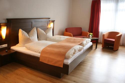 a bedroom with a large bed and a chair at Löwen-Post in Alpirsbach