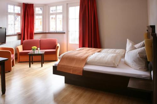 a bedroom with a bed and two chairs and a television at Löwen-Post in Alpirsbach