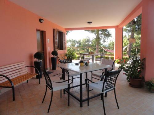 eine Terrasse mit einem Tisch, Stühlen und einer Bank in der Unterkunft Agriturismo Casa Rosa in Offida