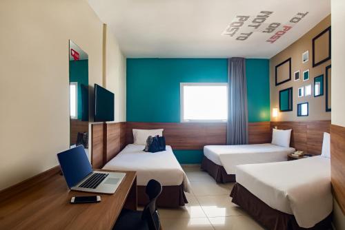 a hotel room with two beds and a laptop on a desk at ibis Styles Ribeirao Preto Braz Olaia in Ribeirão Preto