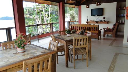 a dining room with a table and chairs and windows at Pousada Casa na Praia in Ubatuba