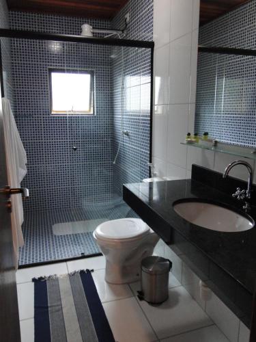 a bathroom with a toilet and a sink and a shower at Pousada Casa na Praia in Ubatuba