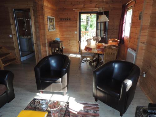 sala de estar con 2 sillas de cuero y mesa en Maisonnette L'Arrivée en Autoire