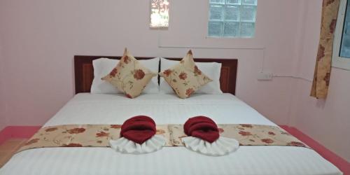 een bed met twee rode handdoeken erop bij hello meme house in Koh Lanta