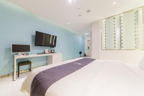 a bedroom with a bed and a desk with a computer at Rosabell Hotel in Ansan
