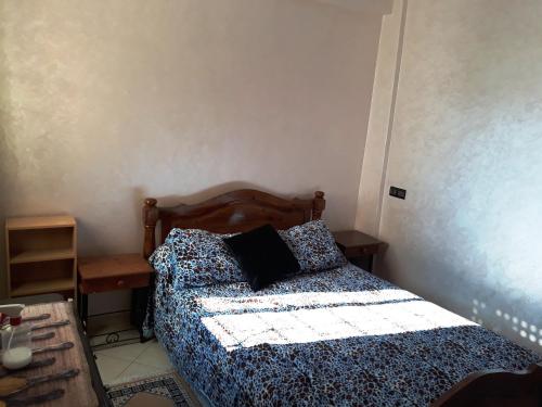 a bedroom with a bed with a blue and white comforter at Appartement Adrar pour Famille in Agadir