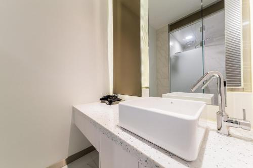a white bathroom with a sink and a mirror at Rosabell Hotel in Ansan