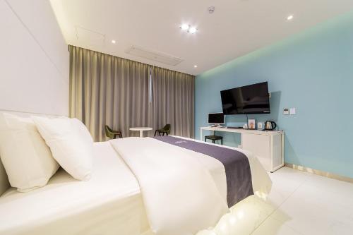 a bedroom with a white bed and a television at Rosabell Hotel in Ansan