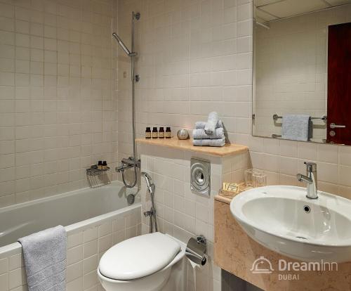 a bathroom with a sink and a toilet and a tub at Dream Inn Apartments - Marina Quays in Dubai